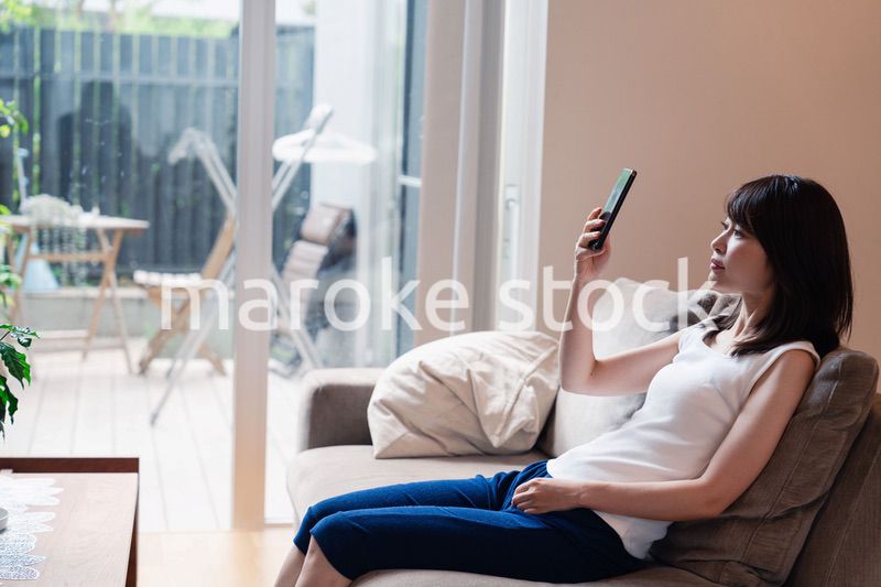 ソファでリラックスしてスマホを使う若い女性