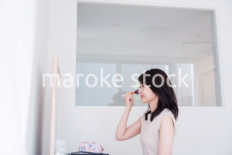 家でメイクをする若い女性