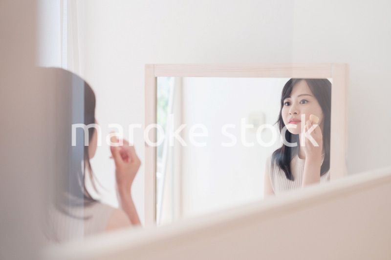 家でメイクをする若い女性