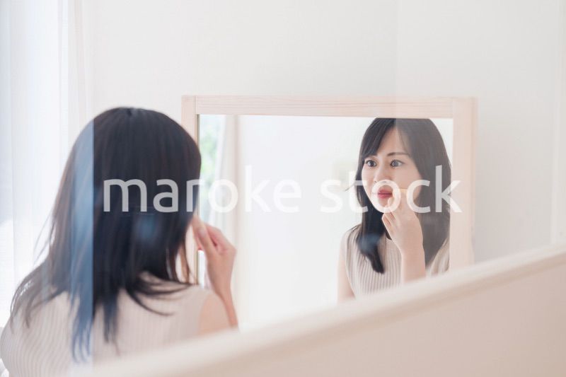 家でメイクをする若い女性