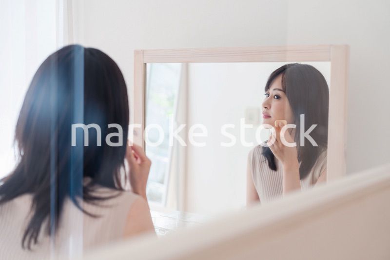 家でメイクをする若い女性