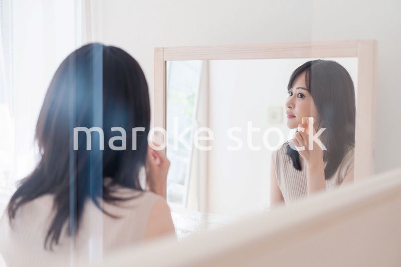 家でメイクをする若い女性