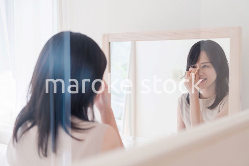 家でメイクをする若い女性