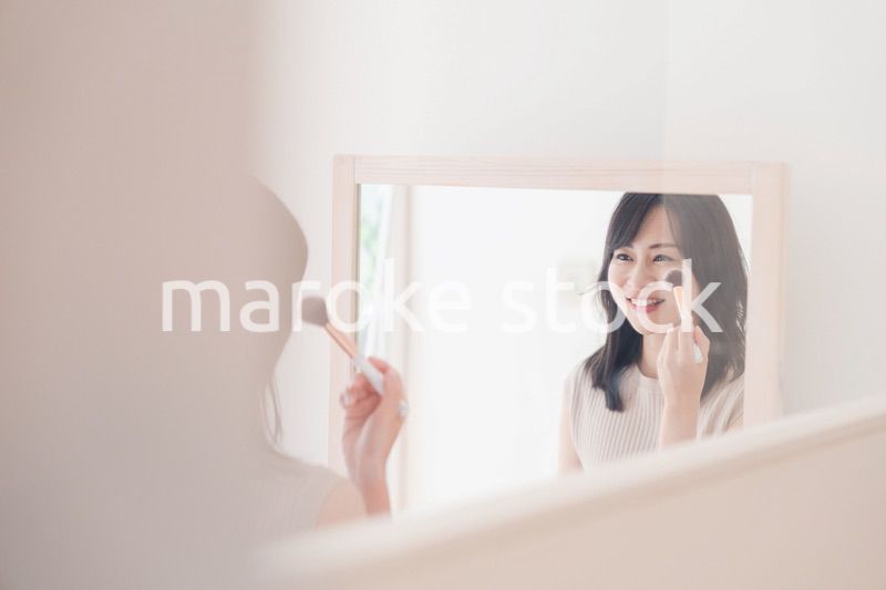 家でメイクをする若い女性