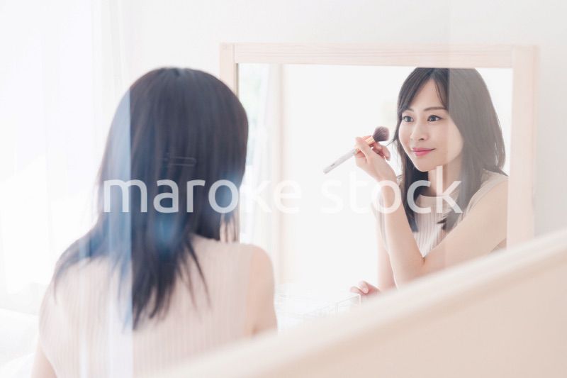 家でメイクをする若い女性