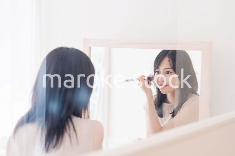 家でメイクをする若い女性