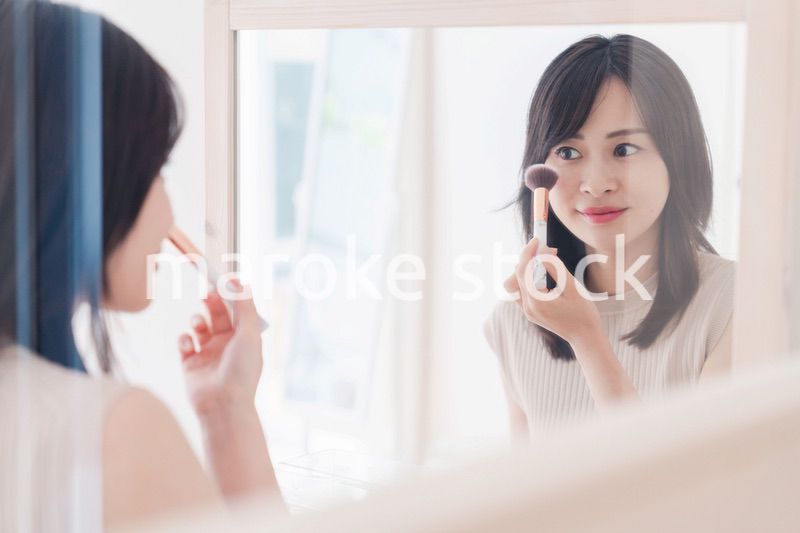 家でメイクをする若い女性