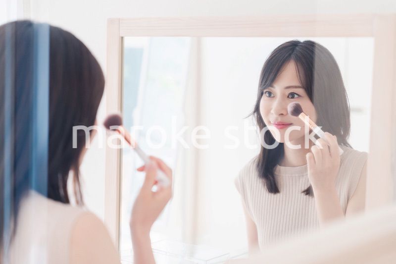 家でメイクをする若い女性