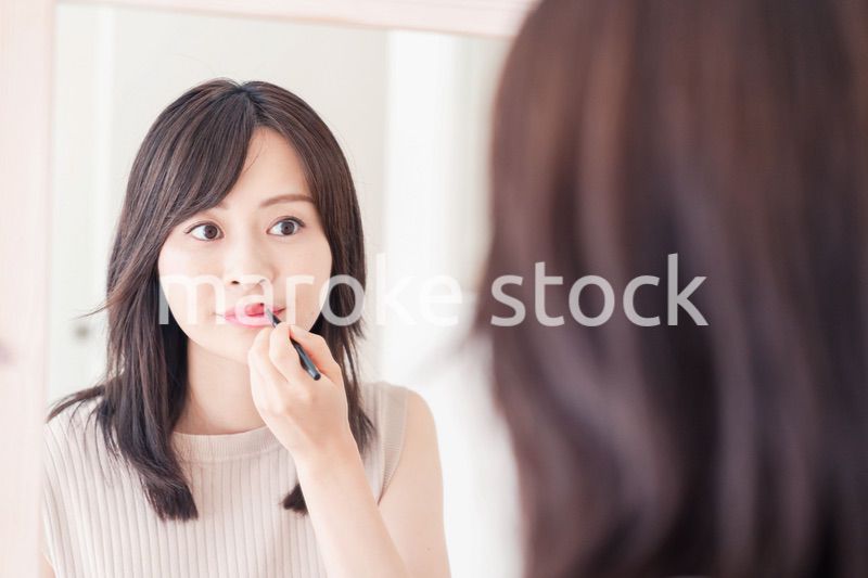 家でメイクをする若い女性