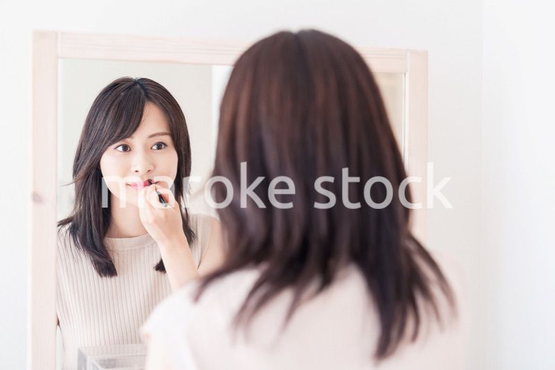 家でメイクをする若い女性