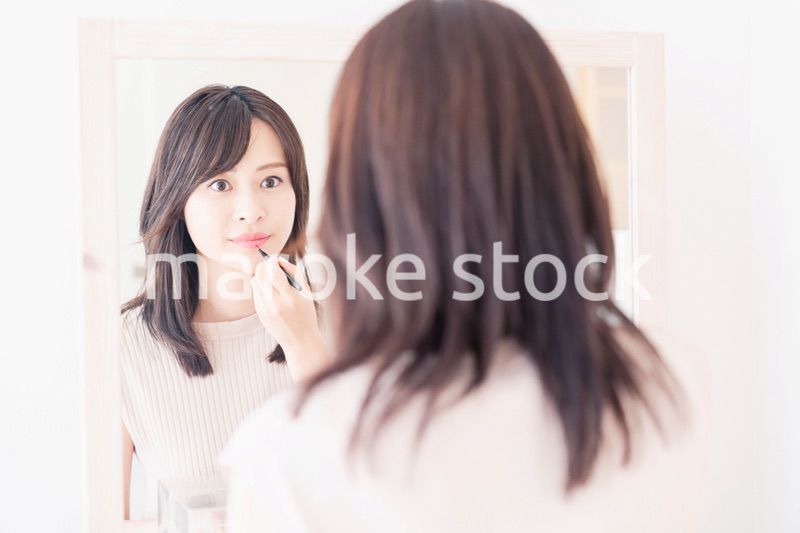 家でメイクをする若い女性