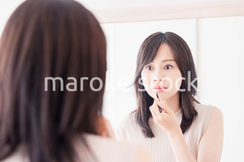 家でメイクをする若い女性