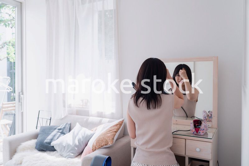 ヘアアイロンを使って髪をセットする若い女性