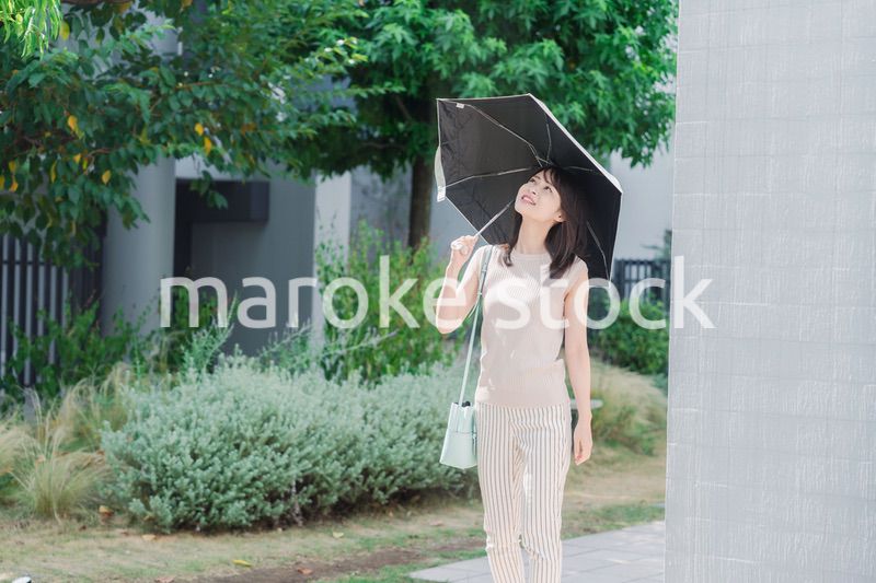 日傘を差して外を歩く若い女性