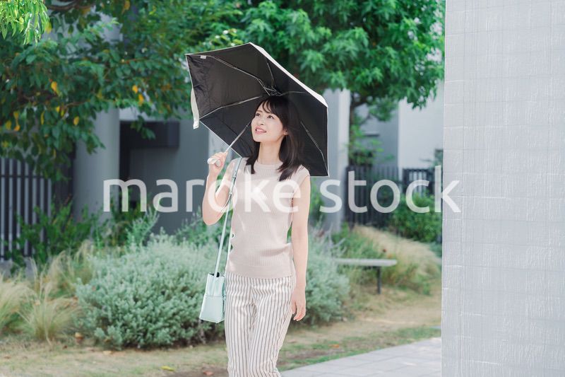 日傘を差して外を歩く若い女性