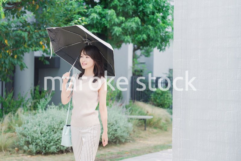 日傘を差して外を歩く若い女性
