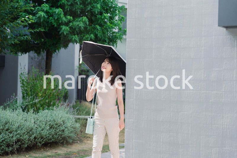 日傘を差して外を歩く若い女性