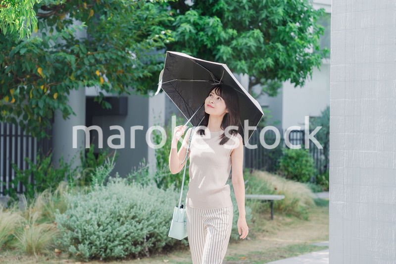 日傘を差して外を歩く若い女性