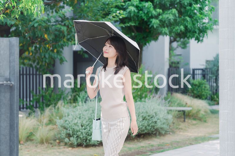 日傘を差して外を歩く若い女性