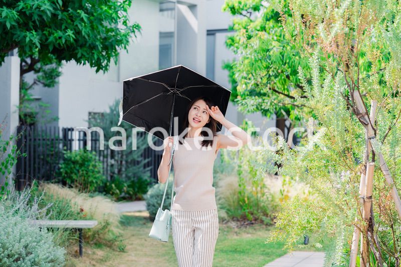 日傘を差して外を歩く若い女性