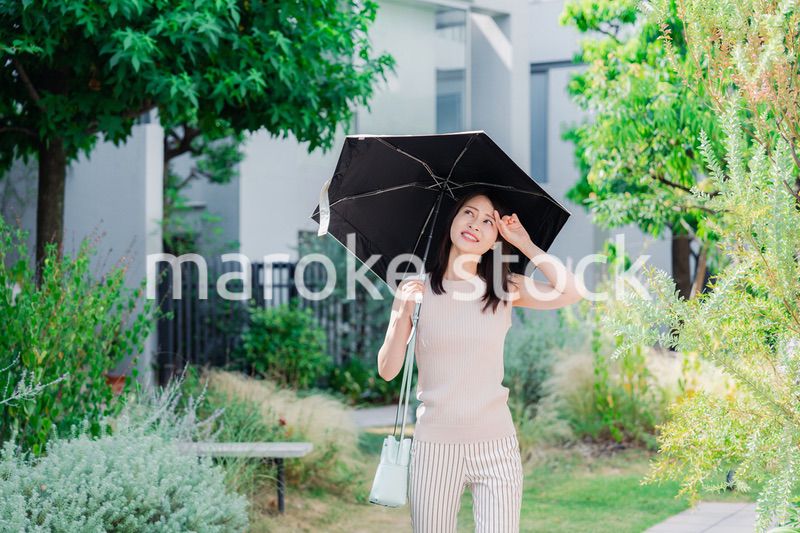 日傘を差して外を歩く若い女性