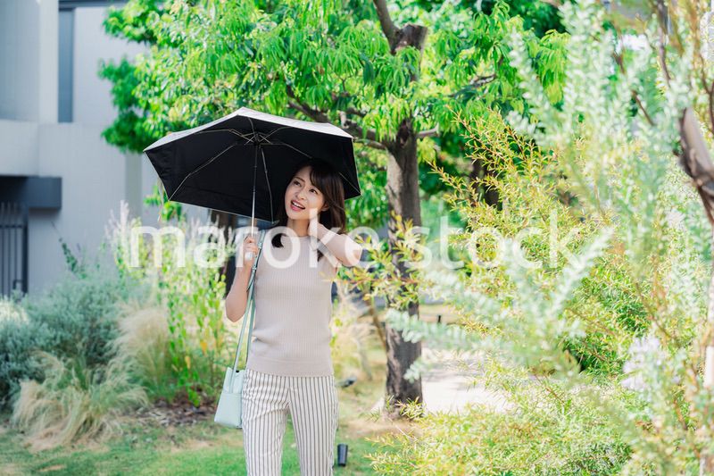 日傘を差して外を歩く若い女性