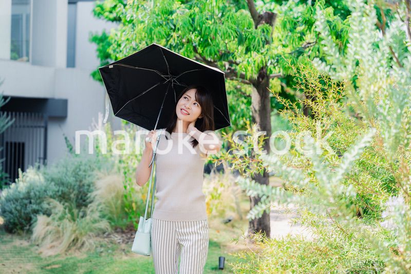 日傘を差して外を歩く若い女性