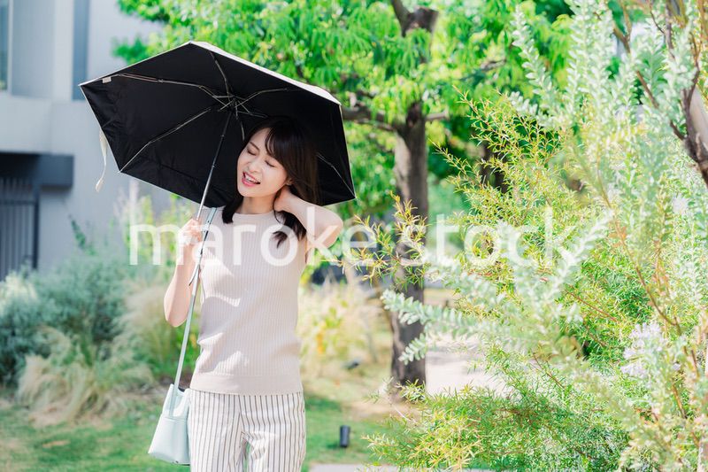 日傘を差して外を歩く若い女性