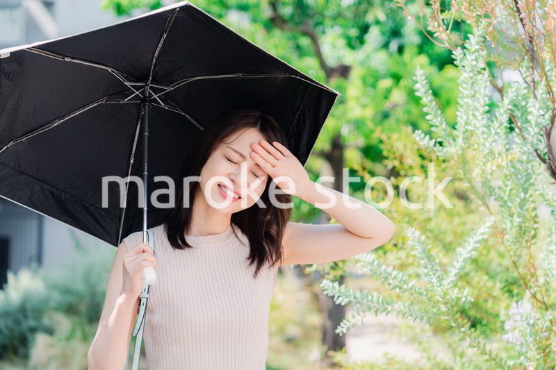 日傘を差して外を歩く若い女性