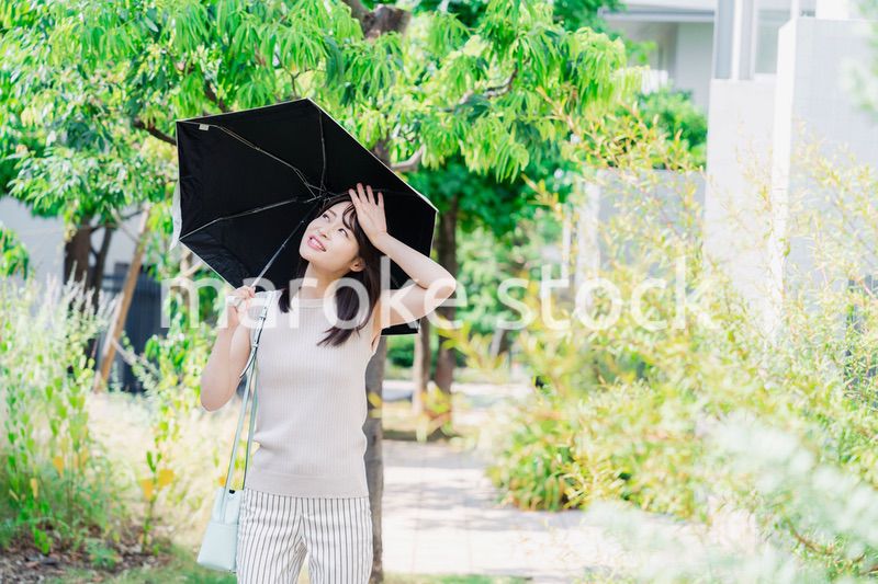 日傘を差して外を歩く若い女性