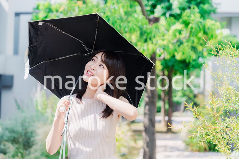 日傘を差して外を歩く若い女性