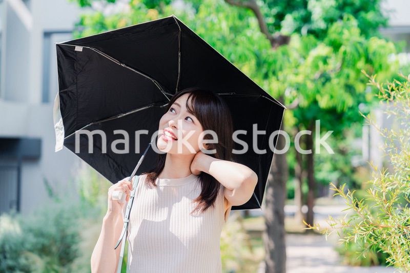 日傘を差して外を歩く若い女性