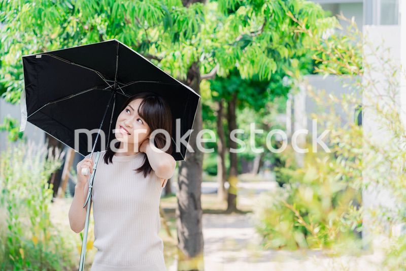 日傘を差して外を歩く若い女性