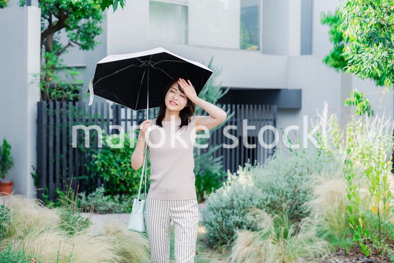 日傘を差して外を歩く若い女性