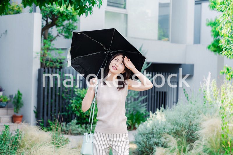 日傘を差して外を歩く若い女性