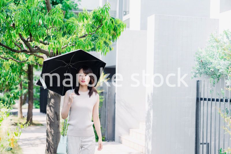日傘を差して外を歩く若い女性