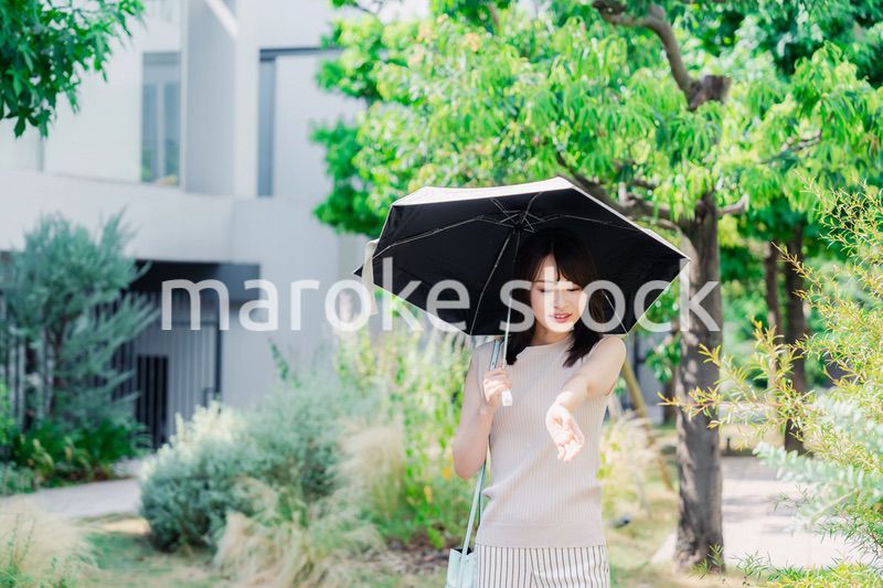 日傘を差して外を歩く若い女性