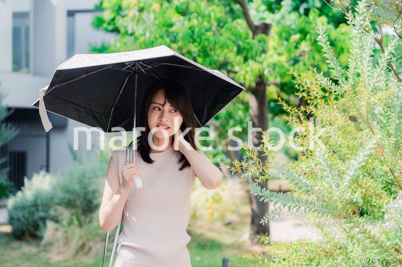 日傘を差して外を歩く若い女性