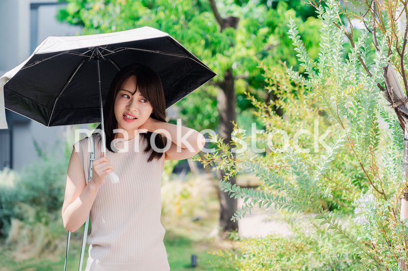 日傘を差して外を歩く若い女性