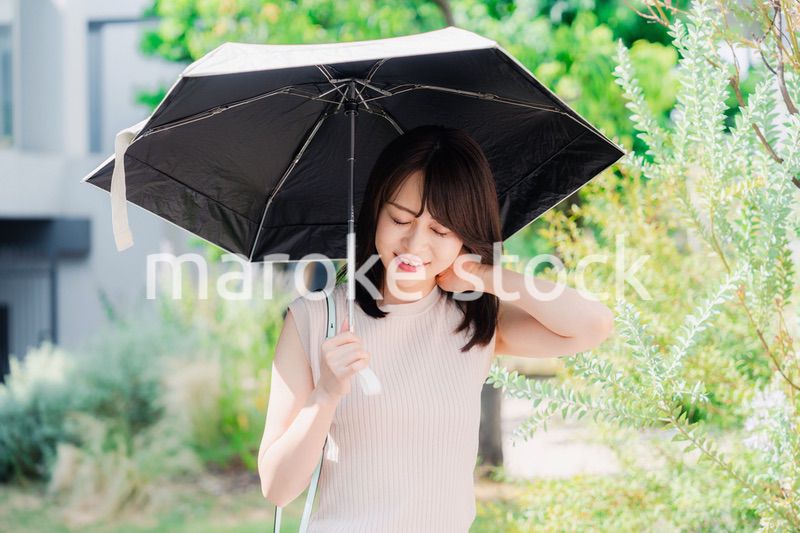 日傘を差して外を歩く若い女性