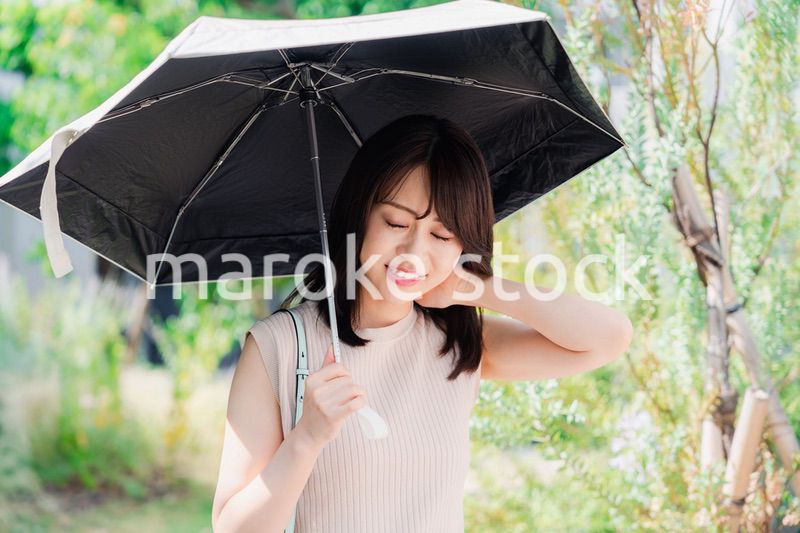 日傘を差して外を歩く若い女性