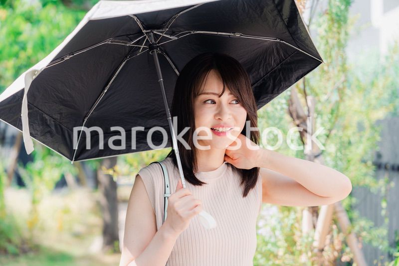 日傘を差して外を歩く若い女性