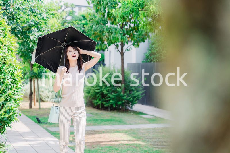 日傘を差して外を歩く若い女性