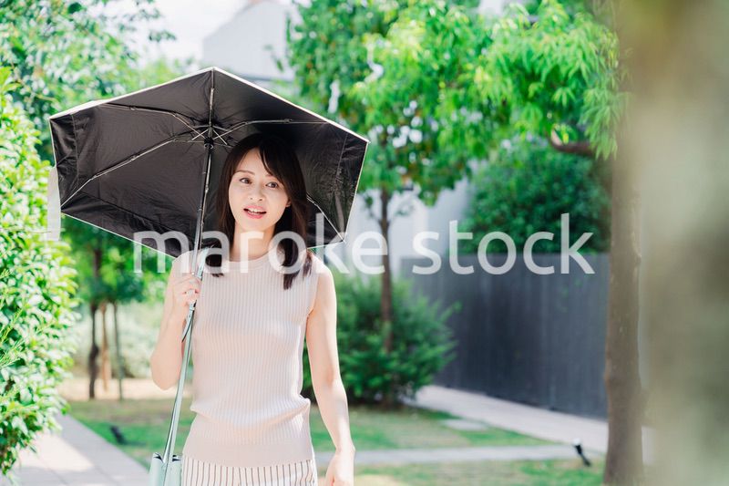 日傘を差して外を歩く若い女性