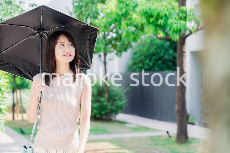 日傘を差して外を歩く若い女性