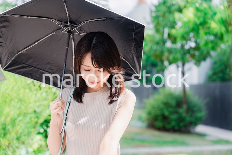 日傘を差して外を歩く若い女性