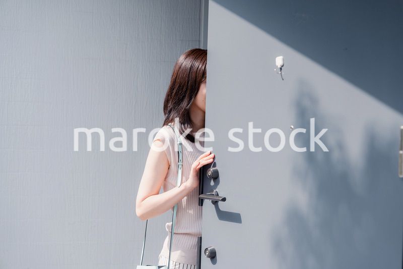 家の玄関ドアを開ける若い女性