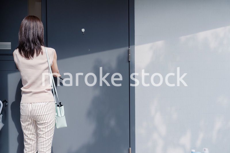 家の玄関ドアを開ける若い女性