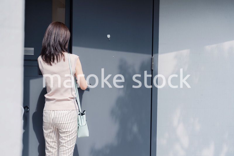 家の玄関ドアを開ける若い女性
