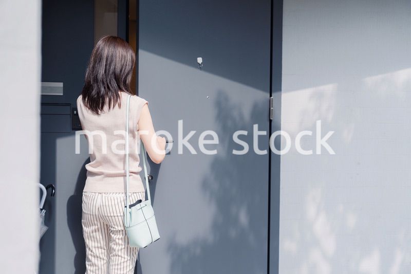 家の玄関ドアを開ける若い女性